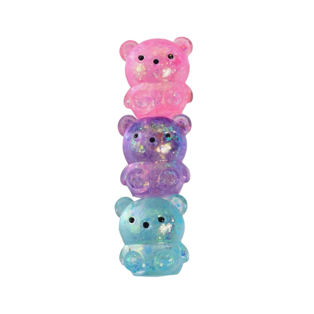 A box of Squeakers 'Sugar Squishy Bears' alongside three translucent glittery bear squishies stacked vertically in pink, purple, and light blue on a white background.