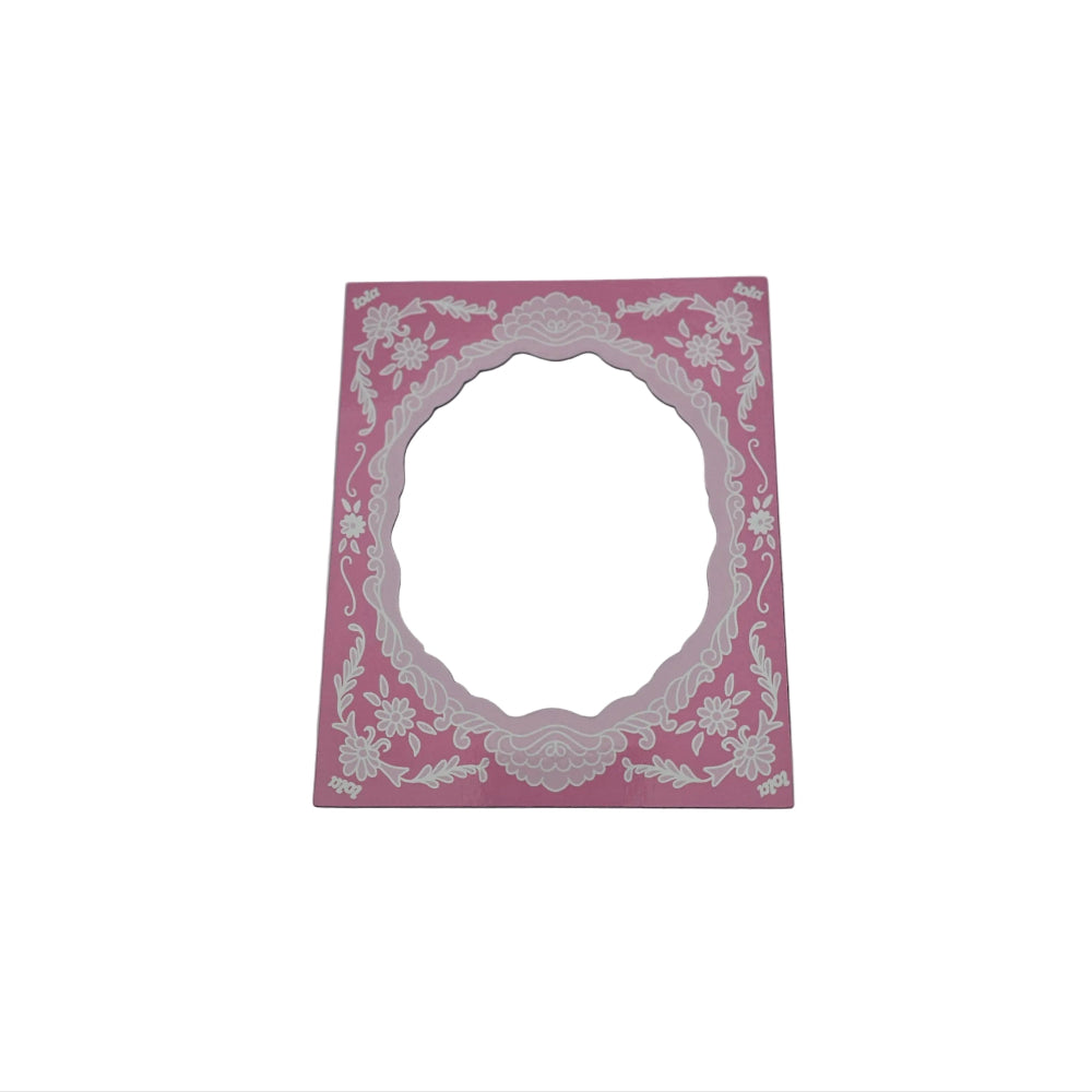 A rectangular pink card or sticker with an ornate white floral border and a scalloped oval cutout in the center, shown on a plain light gray background.