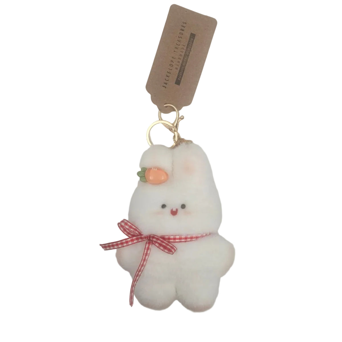 A white plush tooth-shaped keychain charm with a small orange carrot, black eyes, and a red-and-white gingham ribbon on a chef's hat, attached to a gold key ring and a brown paper tag.