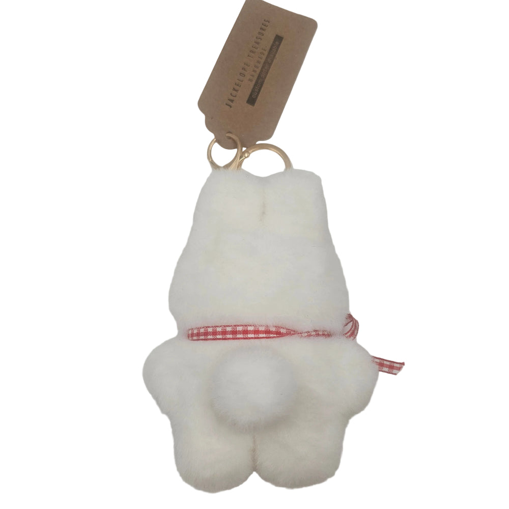 A white fluffy bunny-shaped keychain or bag charm with a red and white gingham ribbon tied around its middle, attached to a gold key ring and a brown paper tag, shown on a plain white background.