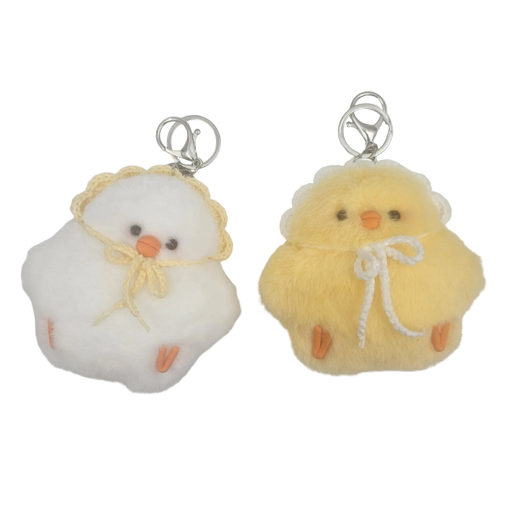 Two fluffy chick-shaped keychain pouches on a plain white background, one white with a yellow bonnet and orange beak/feet, and one pale yellow with a white bow and orange beak/feet.