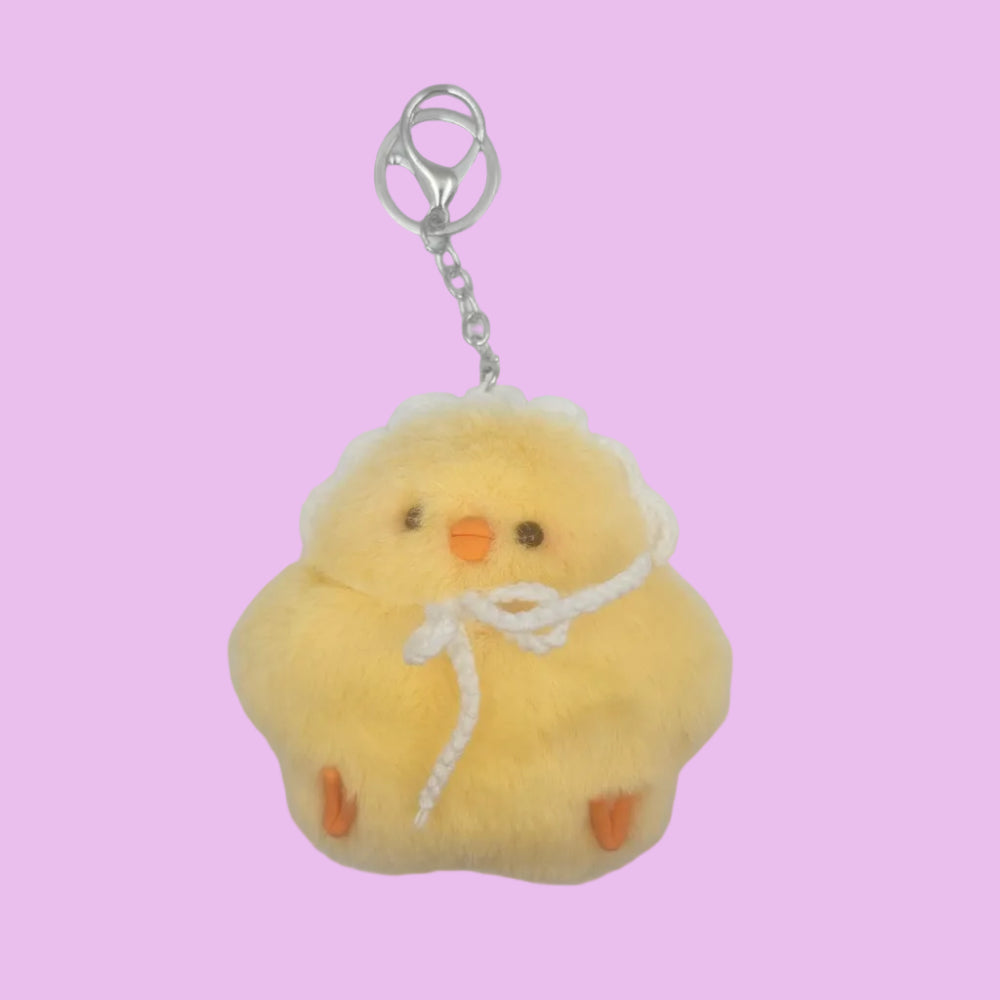 A yellow plush chick keychain charm with embroidered facial features, a white rope bow, and a silver metal key ring, shown on a plain white background.