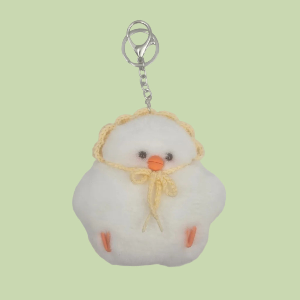 A white fluffy plush keychain bag featuring a cute cartoon face with orange accents, a yellow crocheted hat, and a silver metal key ring clasp, shown on a plain light gray background.