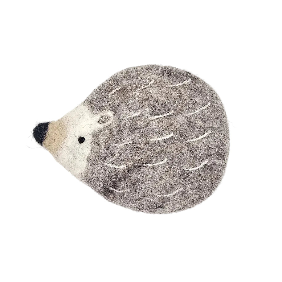 A felt hedgehog-shaped coaster or decorative pad in gray and cream with a black nose, photographed on a clean white background.