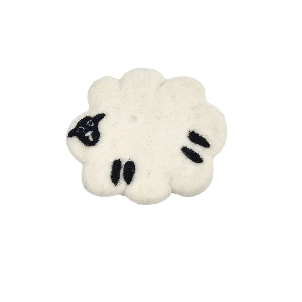 A small felt sheep-shaped coaster, likely a brooch or pin, in off-white wool with black embroidered facial features, shown on a plain white background.