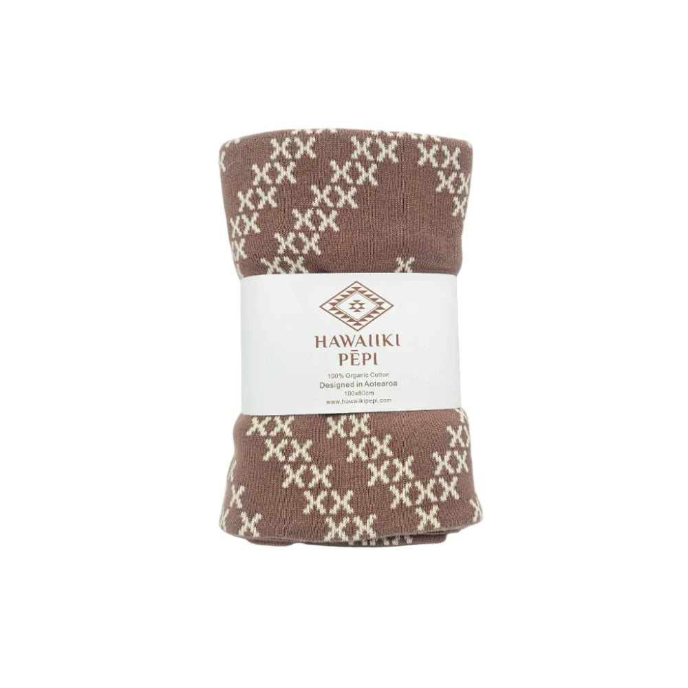 A folded knit blanket with a brown and cream geometric pattern, wrapped in a white paper band labeled 'HAWAUKI PEPI'.