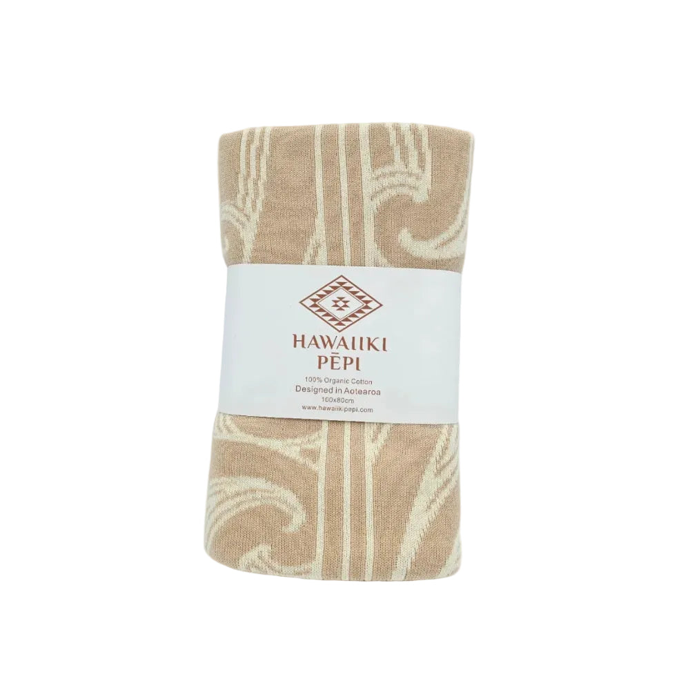 A folded cotton towel with a beige and cream Southwestern pattern, wrapped in a white paper band labeled 'HAWAIIKI PÉPI'.