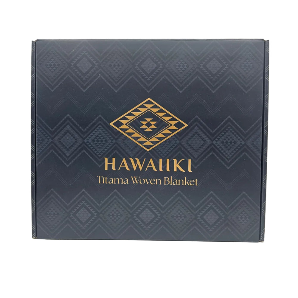 A square dark navy blue product box with a geometric pattern and gold lettering that reads 'HAWAIIKI Titama Woven Blanket'.