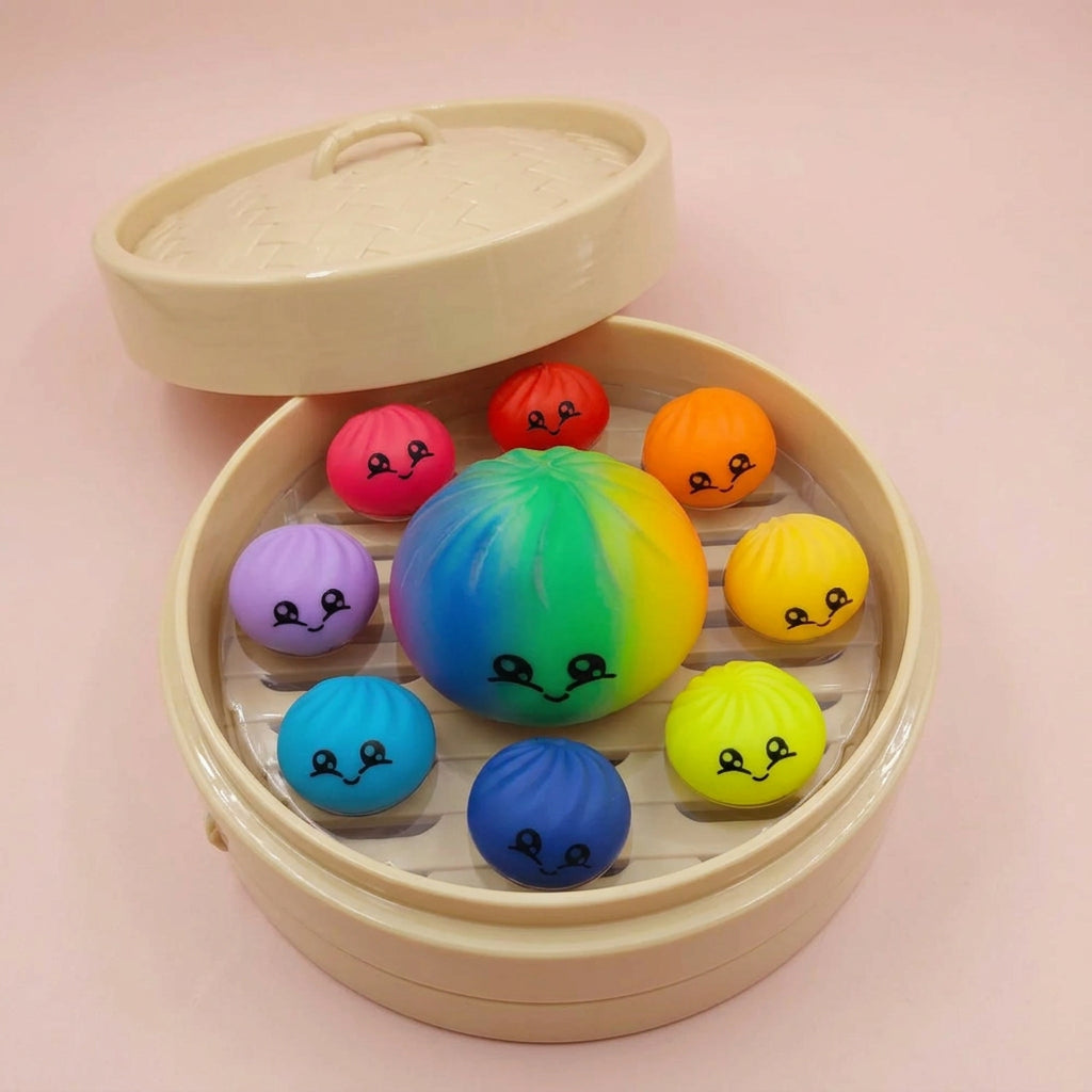 A round beige plastic container with its lid off, filled with colorful spherical squishy toys featuring simple cartoon faces. The toys come in multiple bright colors including yellow, orange, red, green, blue, purple, and light blue, arranged inside a clear plastic liner.