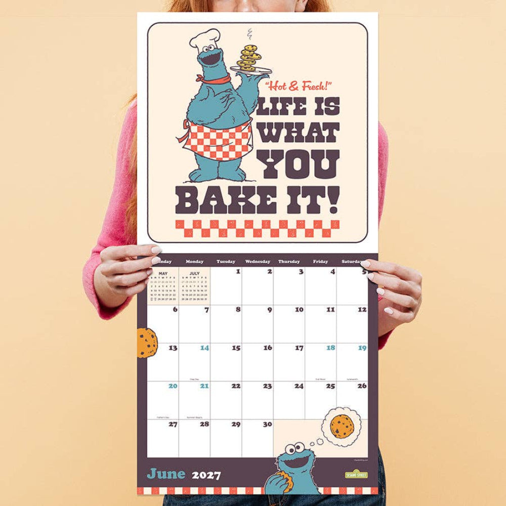 Person holding a calendar with a cartoon character design on a beige background