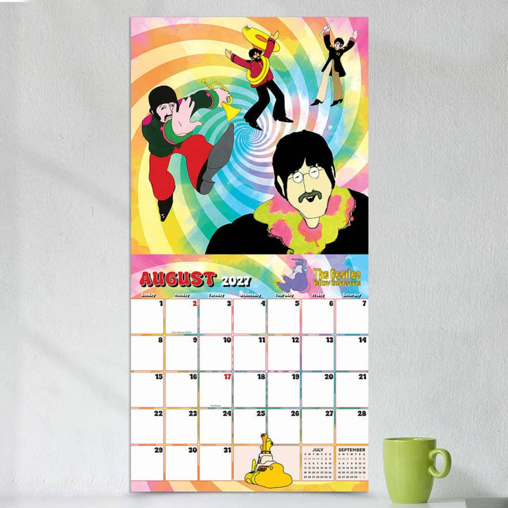 Calendar with The Beatles design on a white wall next to a green mug.