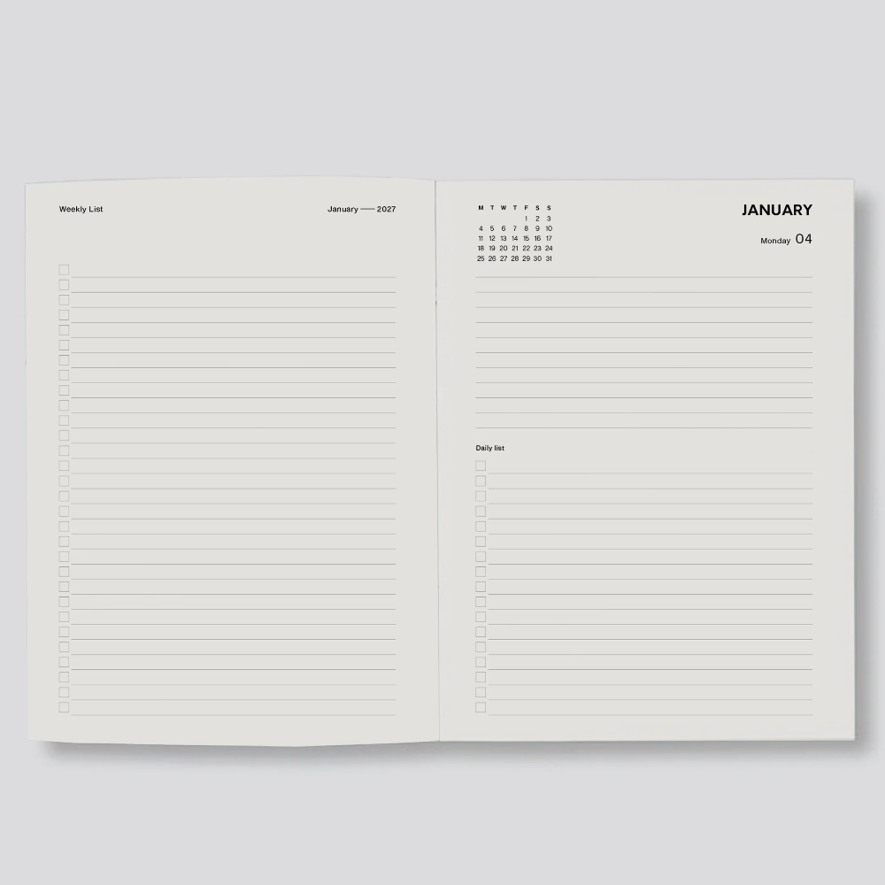An open two-page planner or notebook showing lined writing areas, a small January calendar at the top of the right page, and the word January, photographed on a light gray background.
