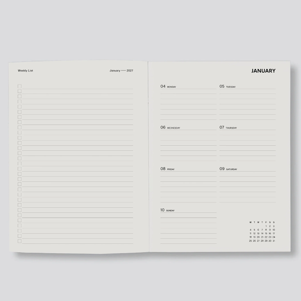 An open planner or notebook showing two interior pages with lined writing areas and a January calendar layout, photographed on a light gray background.