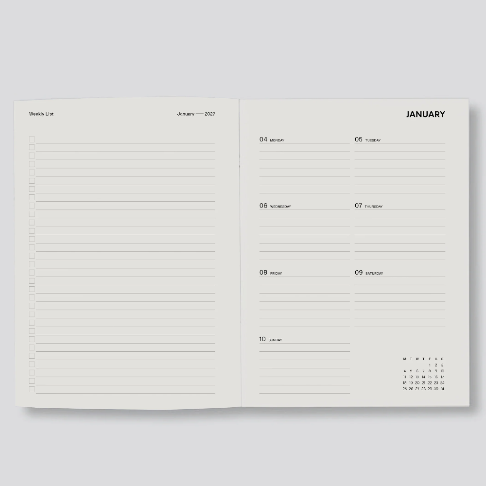 An open planner or notebook showing two interior pages with lined writing areas and a January calendar layout, photographed on a light gray background.
