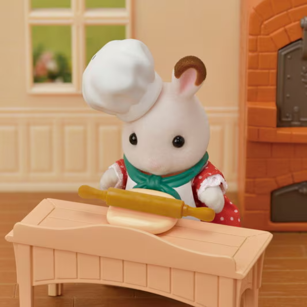 Toy rabbit character in a chef outfit with a rolling pin in a kitchen setting