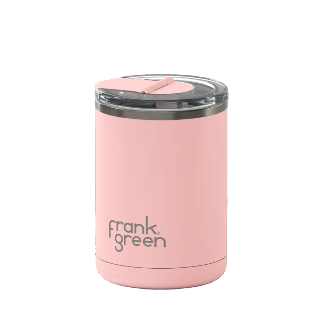 A light pink vacuum-insulated tumbler with a clear lid and a pink flip-top spout, featuring the 'frank green' logo printed in dark gray on the front, set against a solid white background.