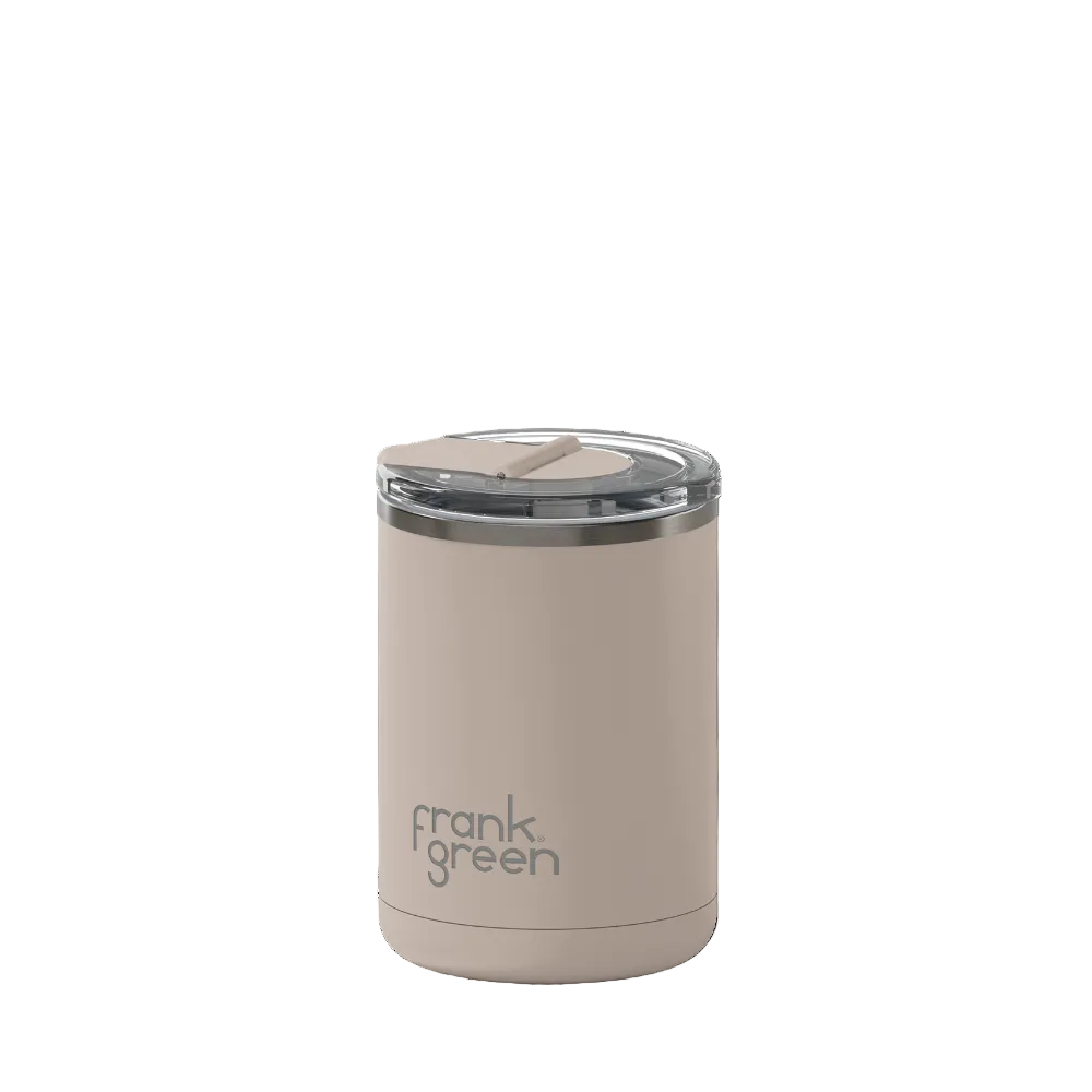 A Frank Green insulated tumbler in a warm beige color, featuring a clear lid with a beige flip straw and a silver rim, set against a plain white background.