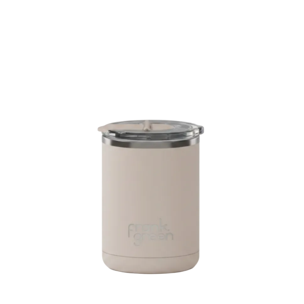 A light beige insulated travel tumbler with a clear lid and a silver metal rim, featuring the 'frank green' logo near the bottom, set against a plain white background.