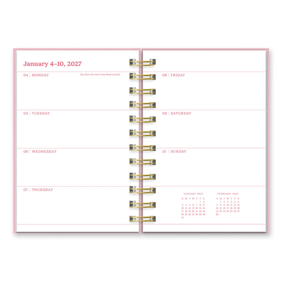 An open ring-bound planner showing a weekly layout for January 4-10, 2027, with pink lines and gold-tone rings on a white page against a light gray background.