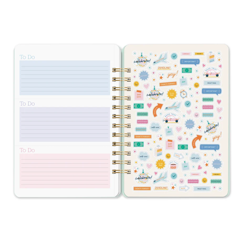 An open spiral-bound planner or notebook showing two decorated pages with pastel lined 'To Do' sections and many colorful travel-themed stickers on the right page, photographed on a clean white background.