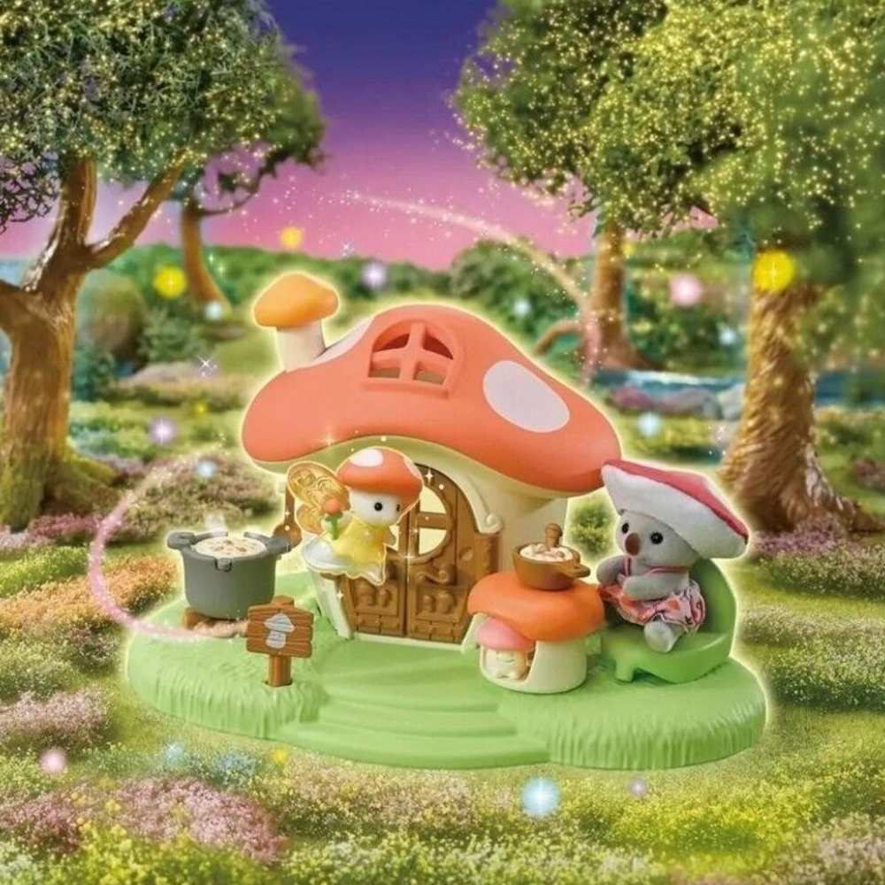 A small fairy-themed mushroom house playset with two tiny animal characters sitting outside the house in a magical forest scene. The house has a large orange-red mushroom cap roof with white spots, a wooden door, and a green grassy base.