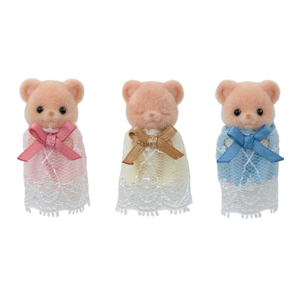 Three small teddy bear figurines standing side by side, each wearing a lace dress and bow. The left bear wears a pink dress and pink bow, the middle bear wears a cream dress with a tan bow, and the right bear wears a light blue dress with a blue bow.