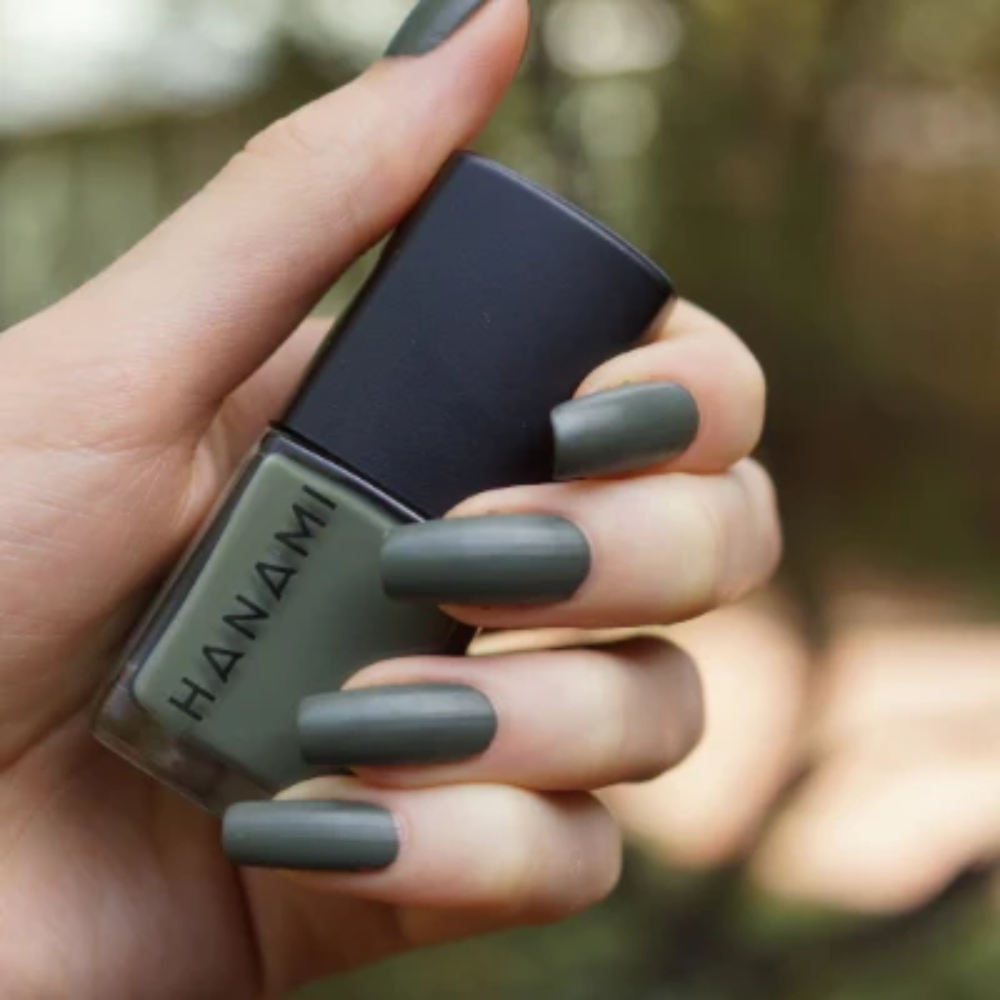 Hand holding a bottle of HANZANI nail polish with matching nails.
