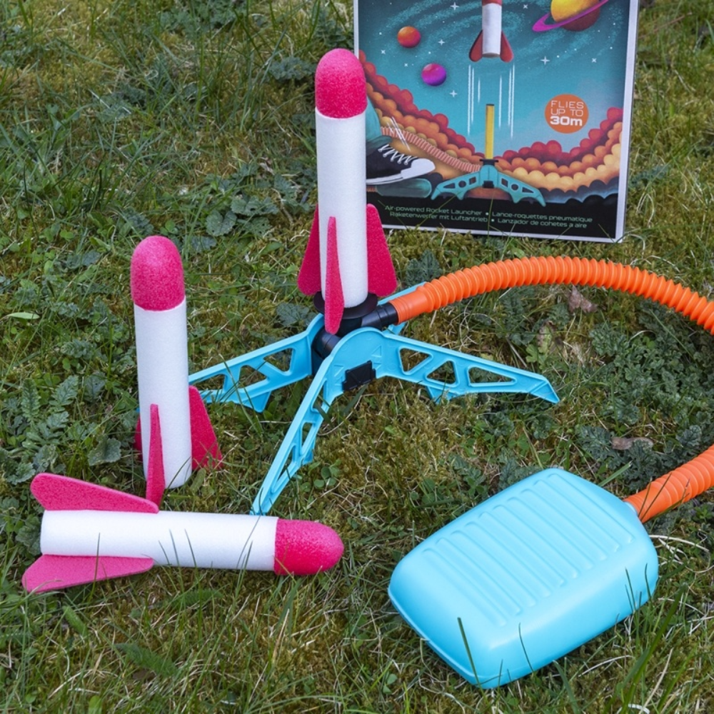 Toy airplane, rocket, and other items on a grassy field with a book in the background.