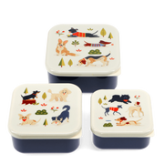 Three square lunch boxes with matching lids arranged on a white background. The boxes have dark navy blue bases and cream-colored lids decorated with colorful illustrations of various dog breeds, trees, and small flowers.