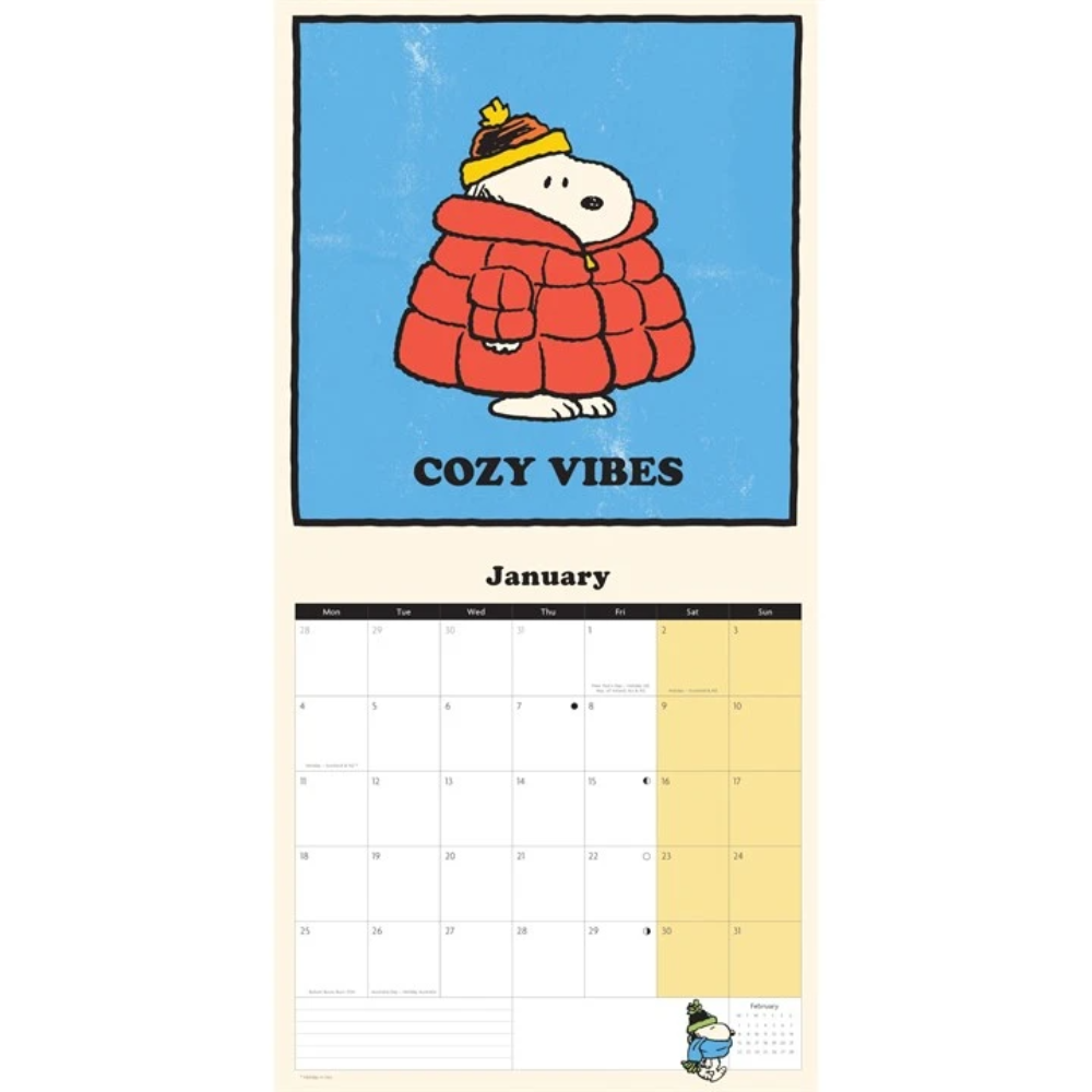 A Peanuts-themed January desk calendar page featuring Snoopy wrapped in a red quilted blanket and yellow hat against a blue background, with the text 'COZY VIBES' and a monthly calendar grid below.