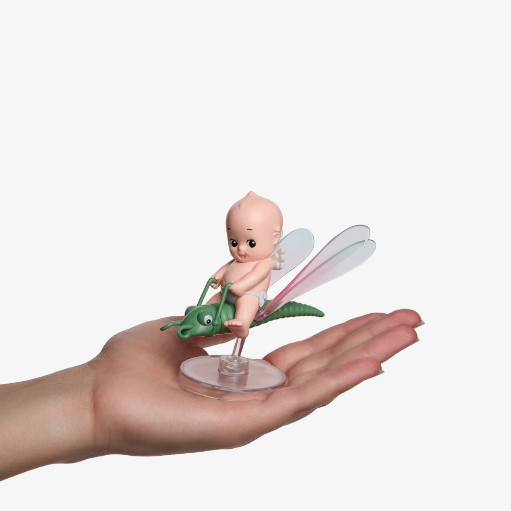 Fairy figurine on a leaf held in a hand against a white background