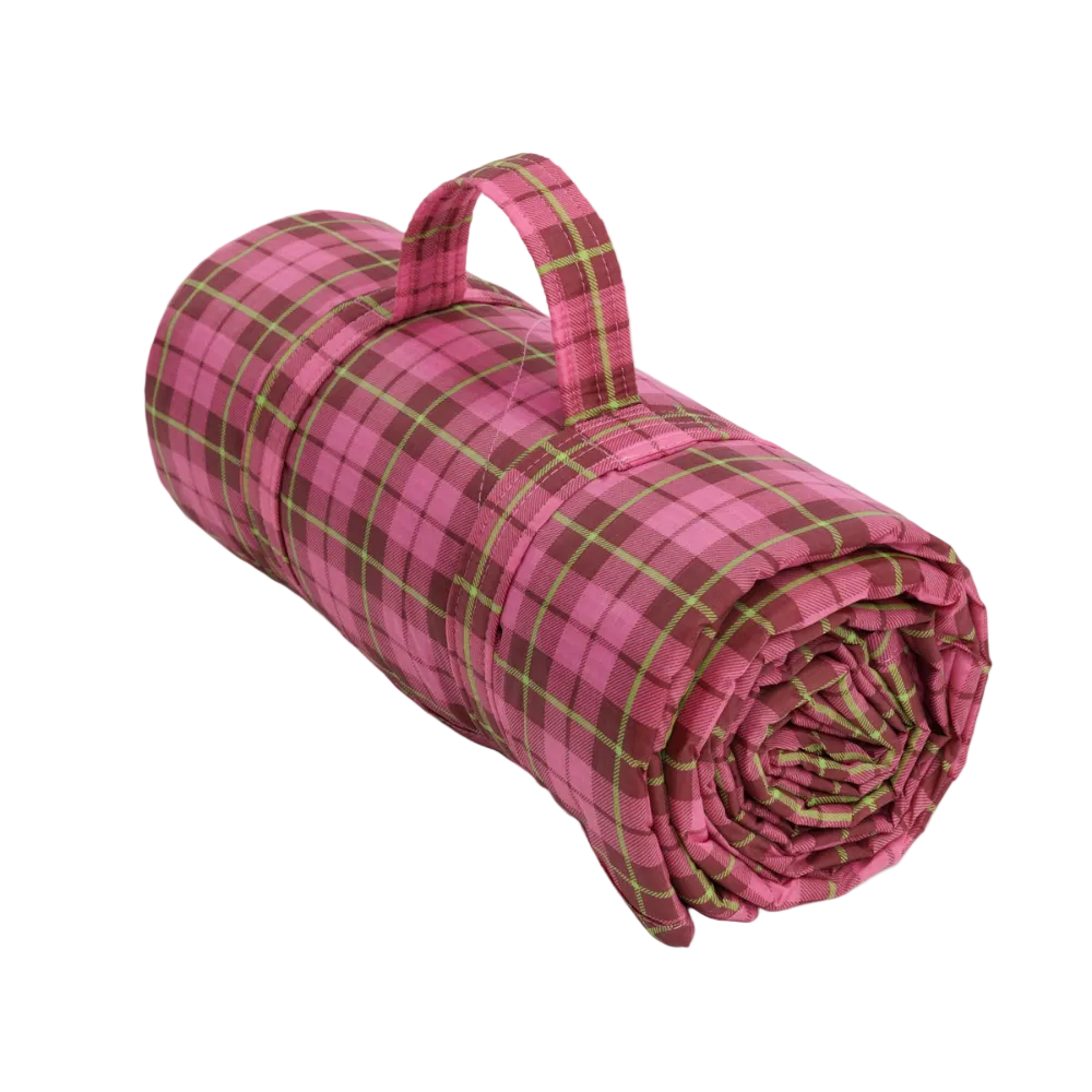 A rolled-up picnic blanket with a pink and green plaid pattern and a fabric carry handle, shown on a light gray background.