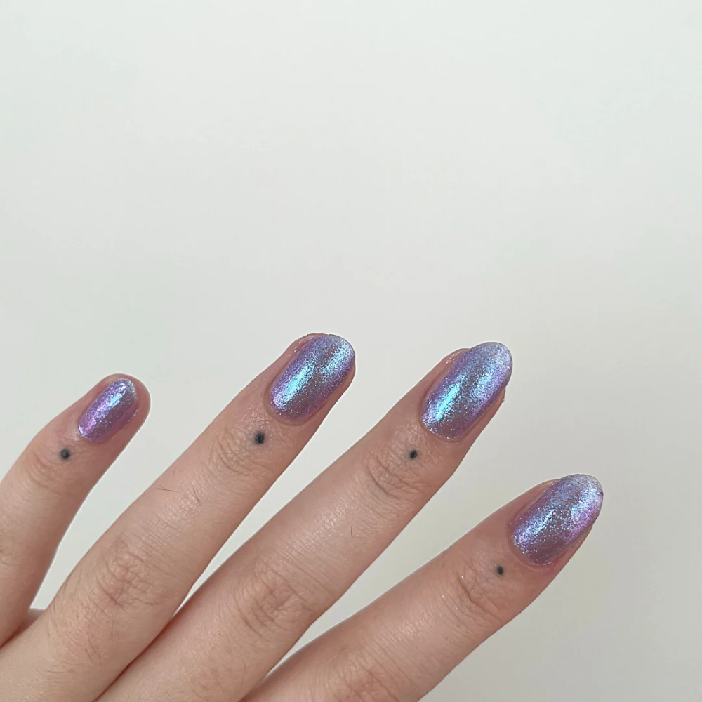 Hand with purple glittery nail polish on a plain background