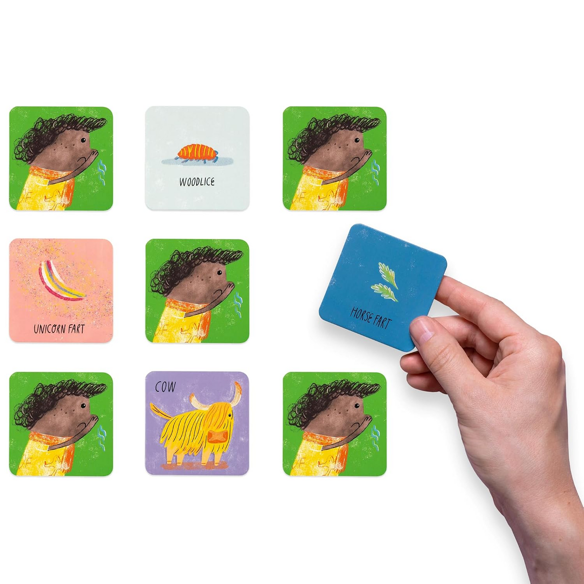 A hand holds a blue card above a grid of illustrated cards on a white background. The cards show whimsical animal and nature illustrations with text such as WOOLACE, UNICORN FACT, and COW.