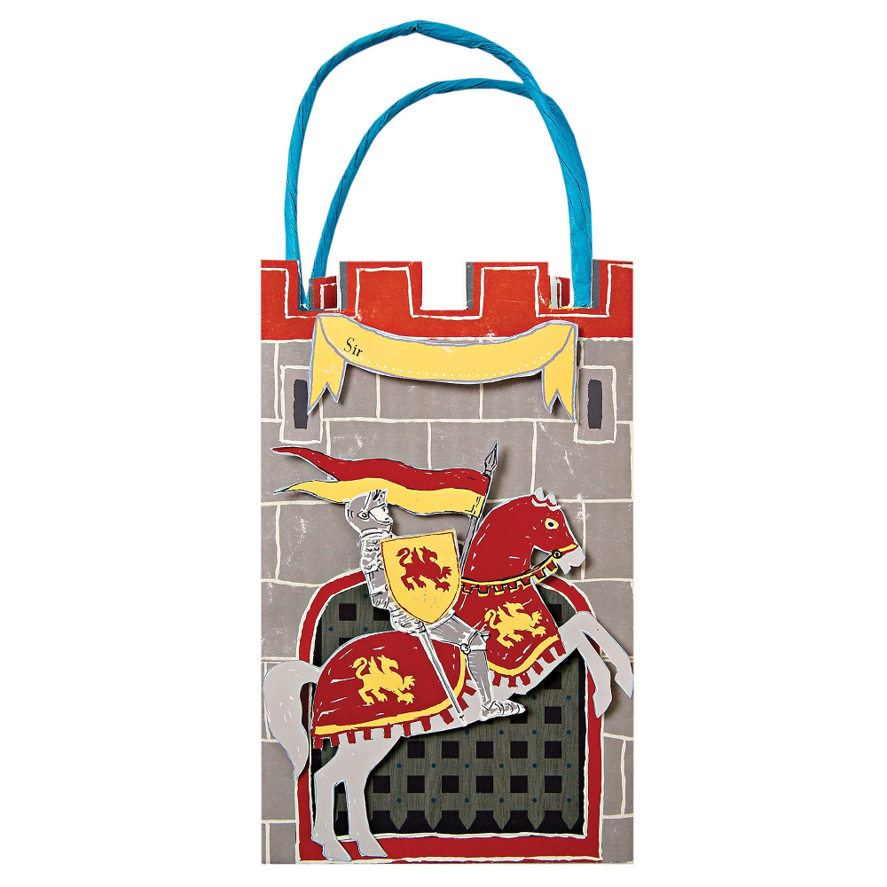 A medieval knight and castle-themed paper bag or gift bag with blue handles, featuring a gray stone wall, red crenellations, a yellow banner, and a knight in red and gold armor on a white background.