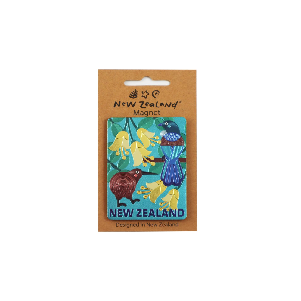 A New Zealand-themed enamel magnet on a brown kraft cardboard hanger card. The magnet features colorful illustrations of a kiwi bird, a blue-tailed native bird, and yellow flowers on a teal background, with 'NEW ZEALAND' printed at the bottom.