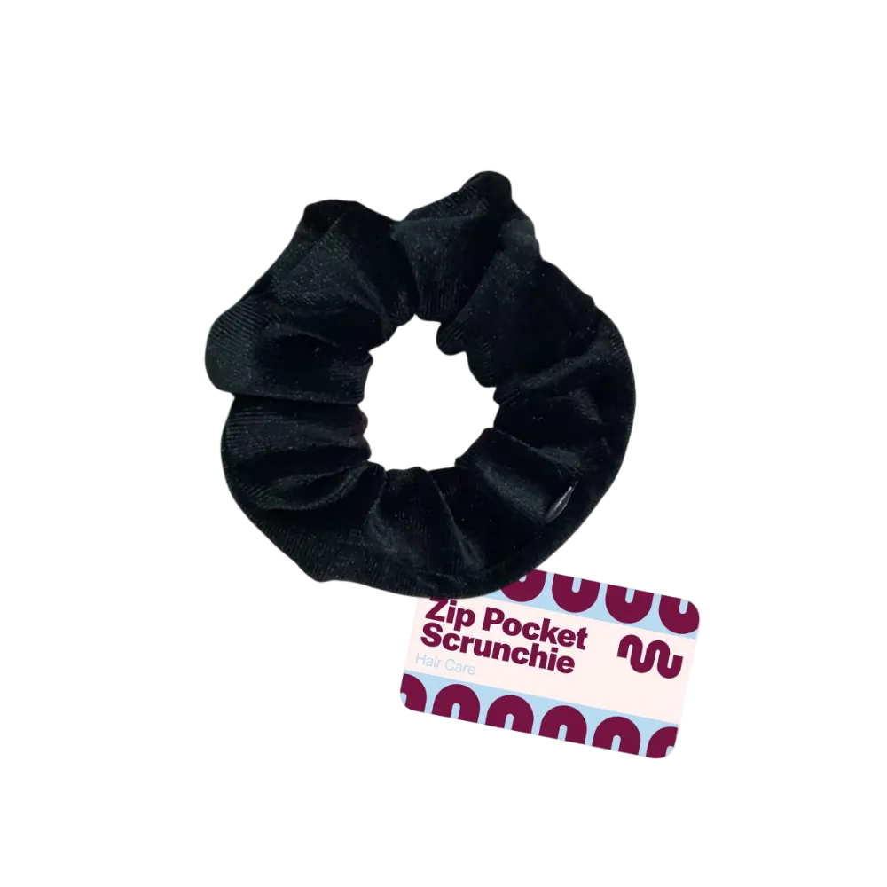 A black velvet hair scrunchie with a zippered pocket, shown on a white background with its product tag.