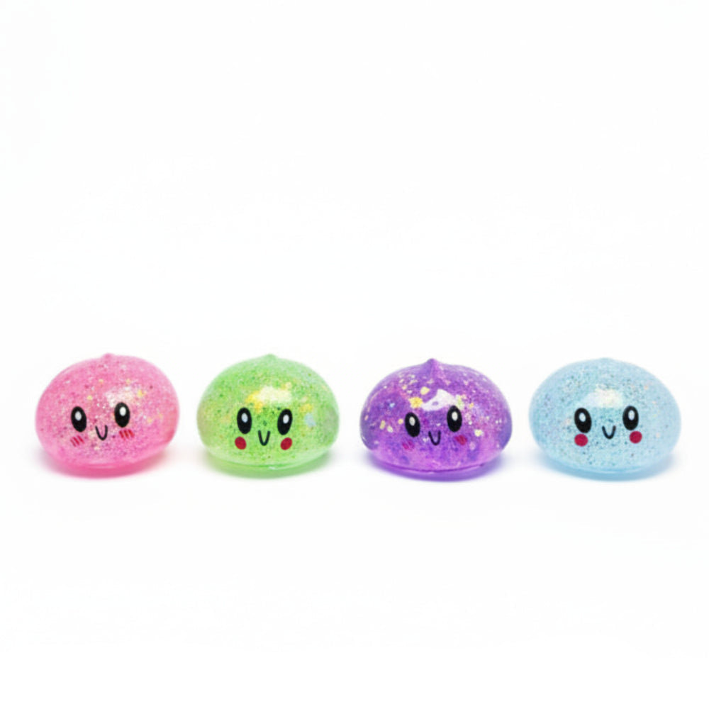 A display box of cute, food-shaped squishy toys with a hand holding one pink glittery toy, and four small squishies in pink, green, purple, and blue arranged in front on a white background.