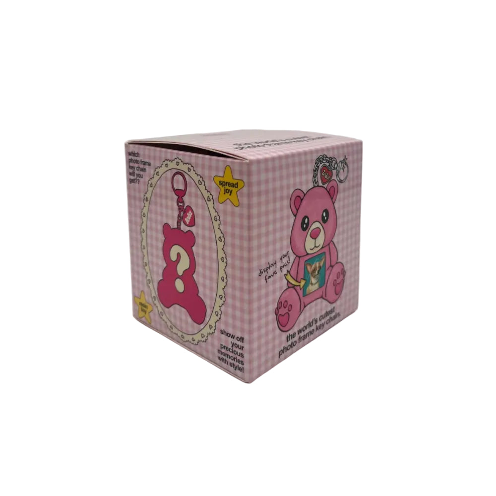 A pink gingham blind box featuring cartoon teddy bear illustrations and a large question mark on the front, photographed on a light gray studio background.