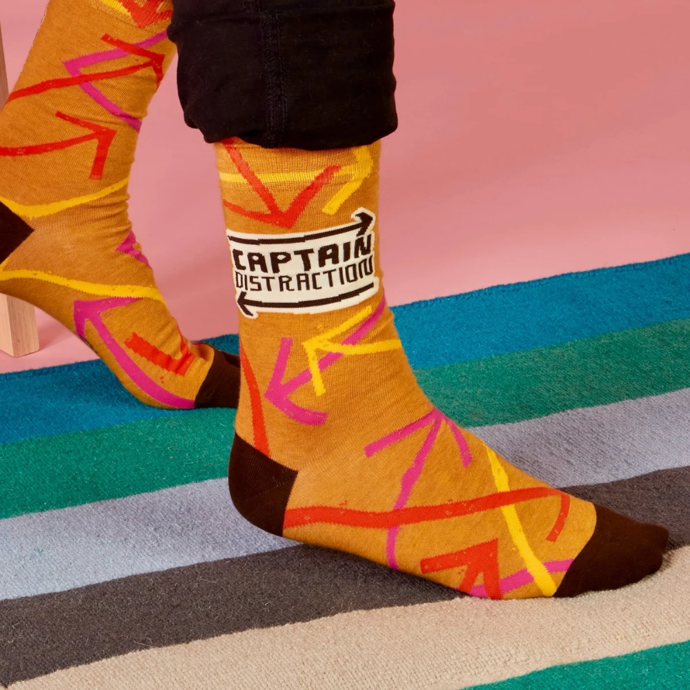 Colorful sock with 'Captain Distraction' text on a multicolored striped floor.