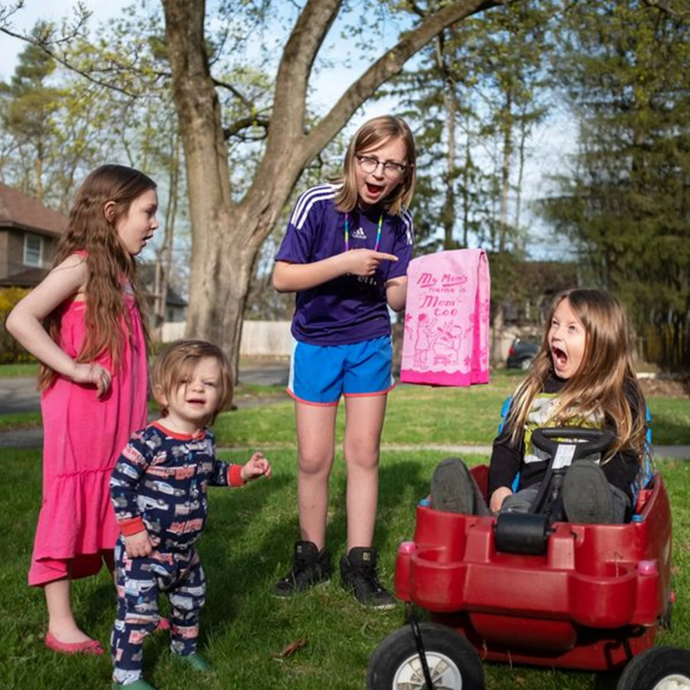 Children playing outdoors with a red wagon in a park setting.