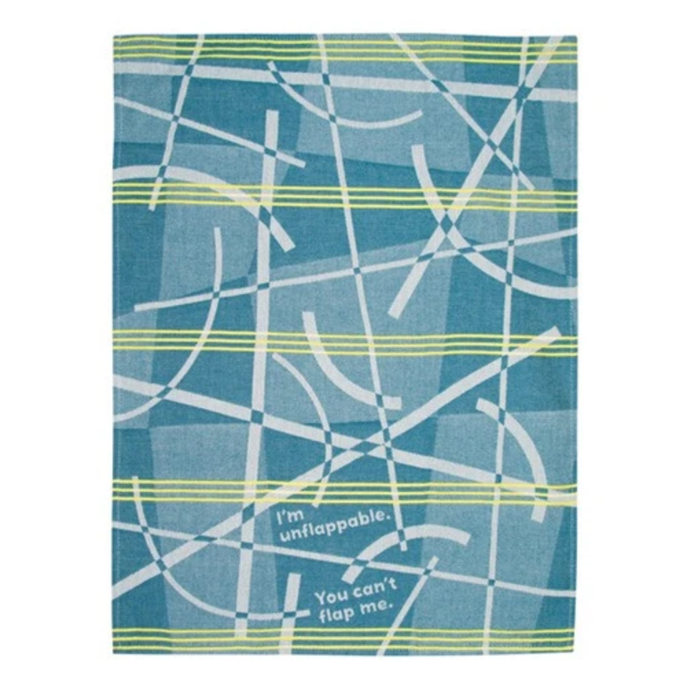 A rectangular fabric item, likely a tea towel or kitchen towel, featuring a blue and teal plaid pattern with white and light green intersecting lines and text that reads 'I'm unflapable. You can't flap me.