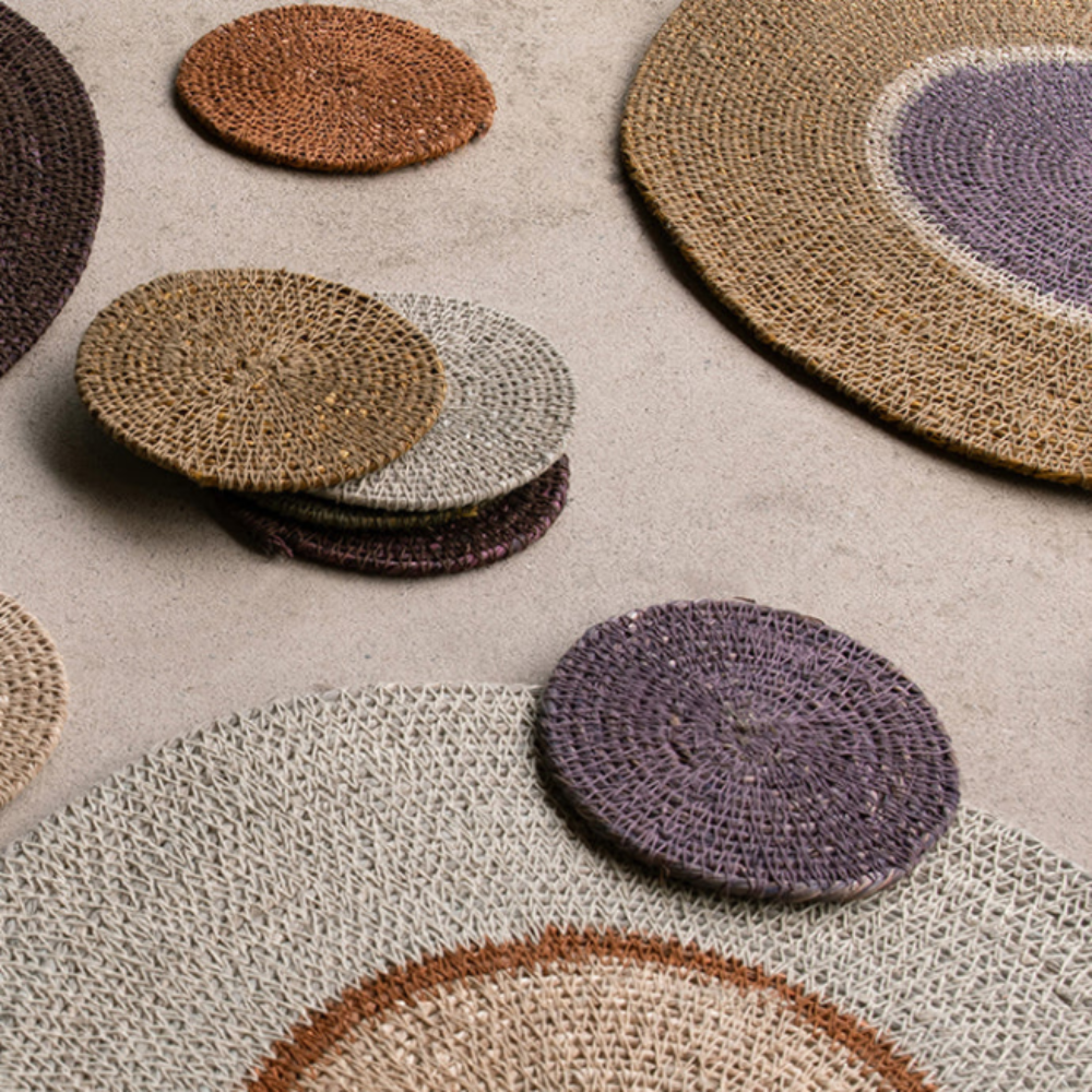 Round woven placemats in various colors on a neutral surface
