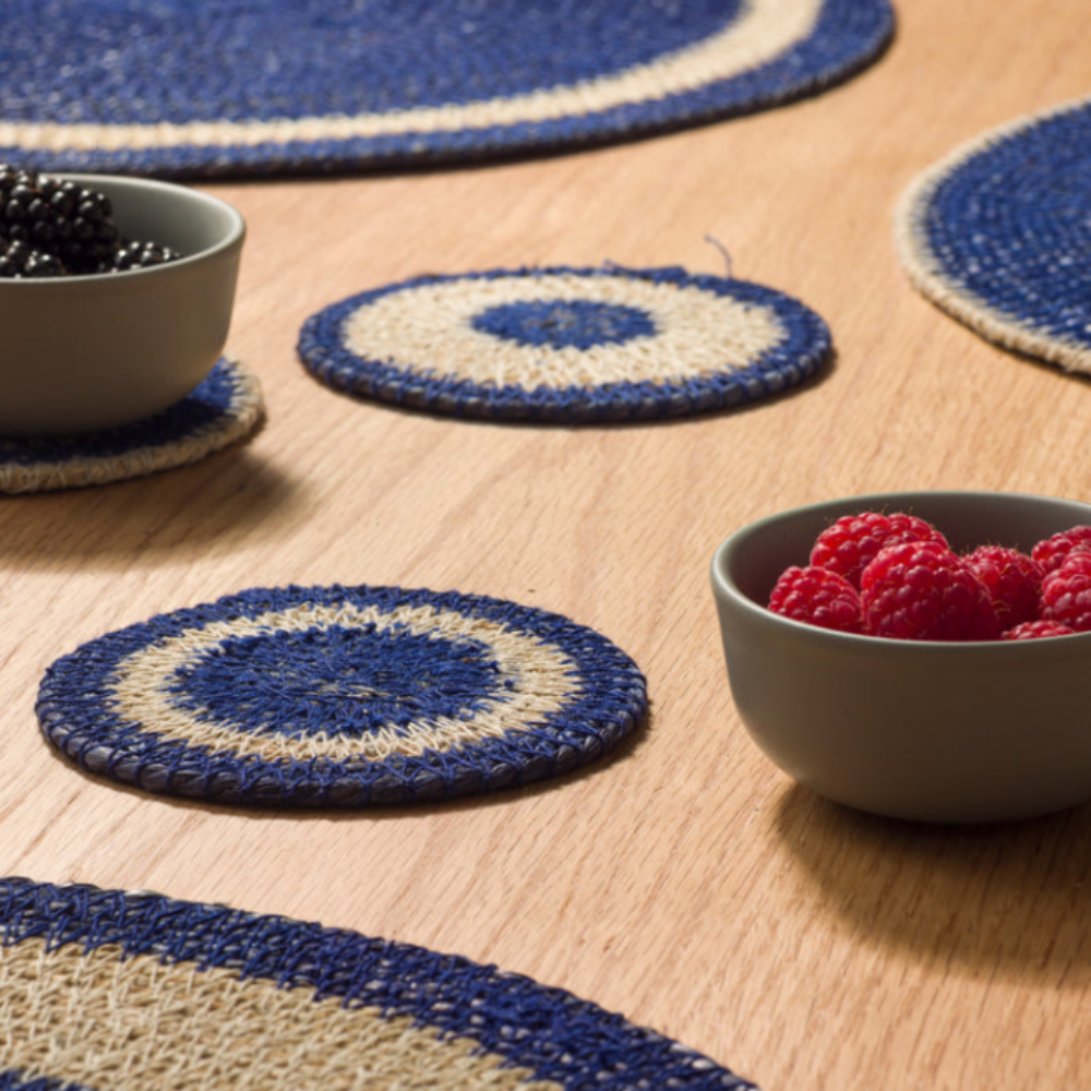 Round blue and beige placemats on a wooden table with bowls of berries.