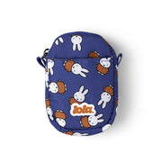 A small blue crossbody pouch featuring a repeating pattern of white rabbits and brown backpacks, with a white 'lola.' logo patch on the front, set against a plain white background.
