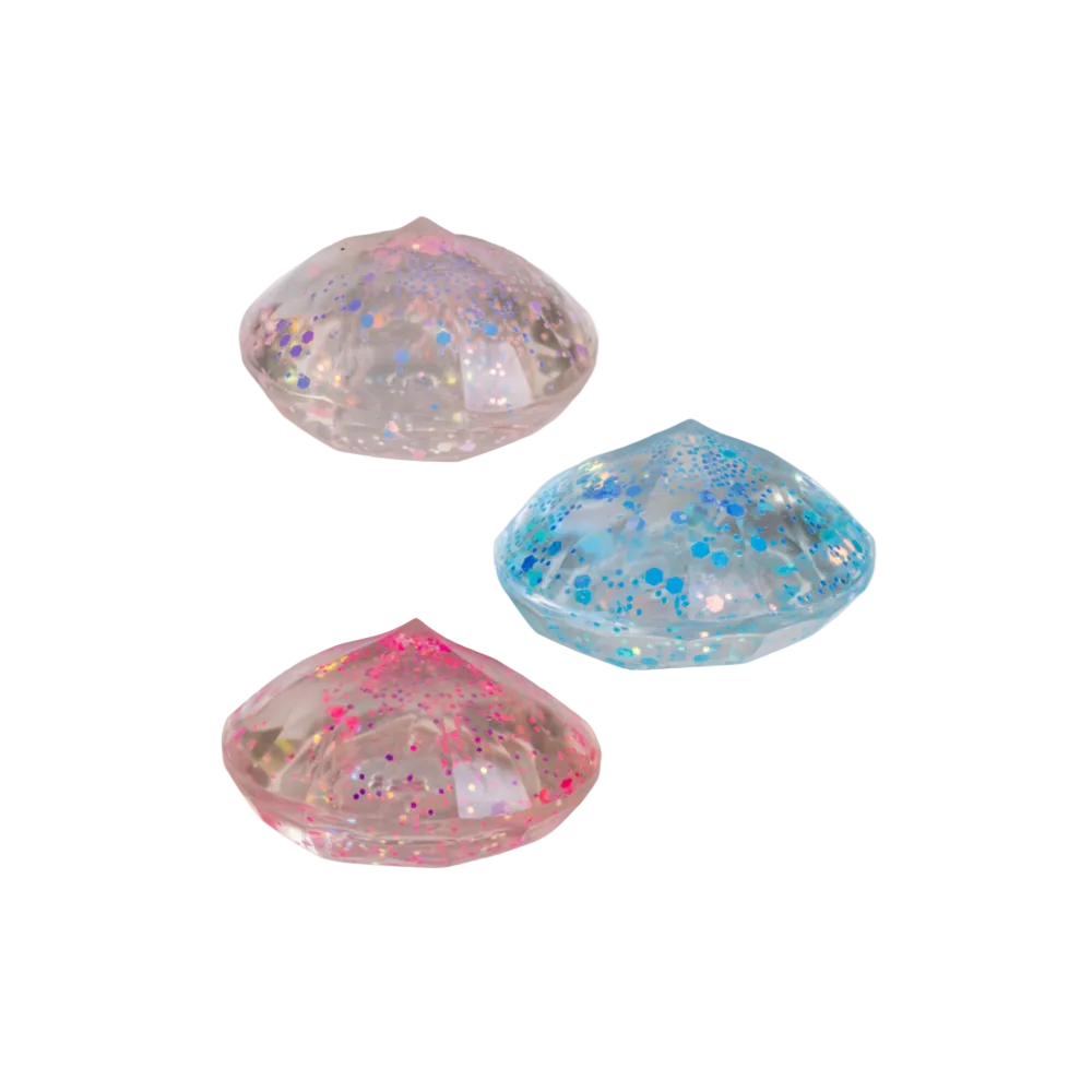 Three colorful, glittery shell-shaped objects on a white background