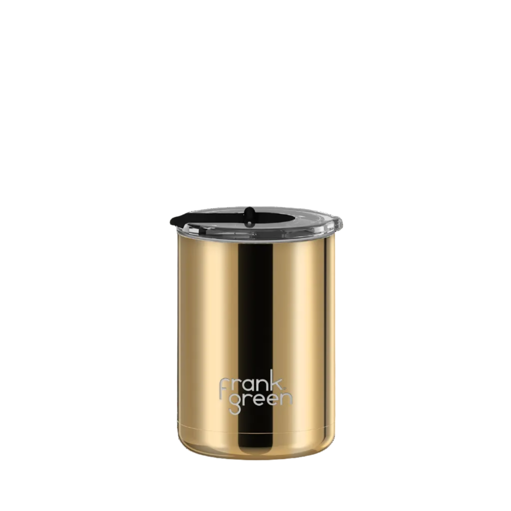 A gold stainless steel travel tumbler with a black lid and a vertical black stripe, featuring the 'frank green' logo near the bottom, set against a plain white background.