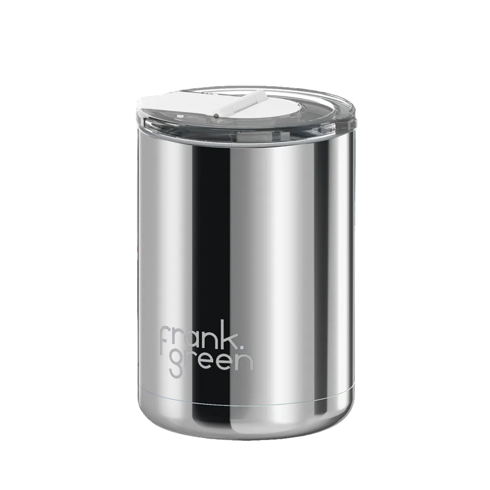 A stainless steel travel tumbler with a clear lid and the 'frank green' logo printed on the front, set against a solid white background.
