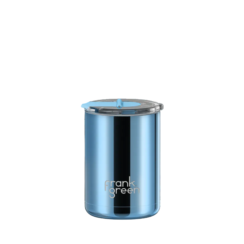 A blue metallic vacuum-insulated tumbler with a clear lid and light blue straw, featuring the 'frank green' logo near the bottom, set against a plain white background.