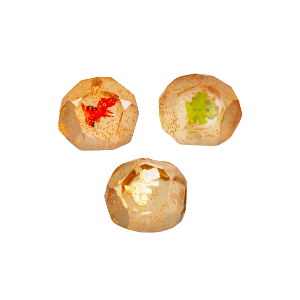 Three faceted clear resin eggs with gold speckles, each containing a small dinosaur figure in different colors: red, green, and orange.